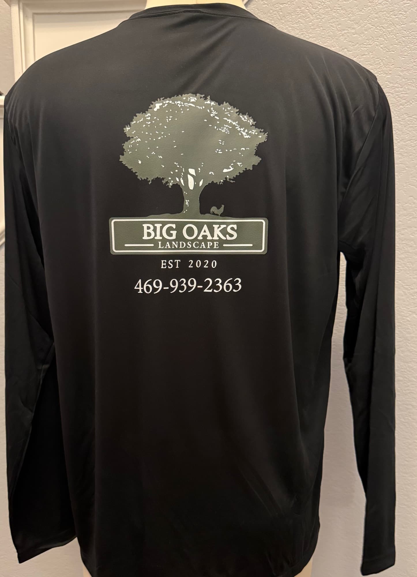 Back of a Big Oaks Landscape shirt with the full-size tree logo and phone number printed across the shoulders